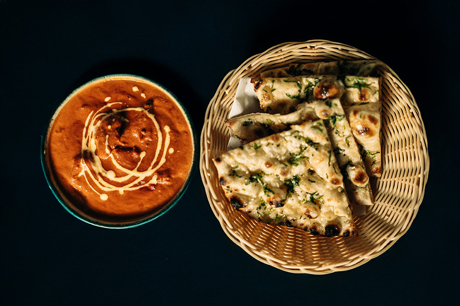 Butter chicken served with a basket of garlic naan