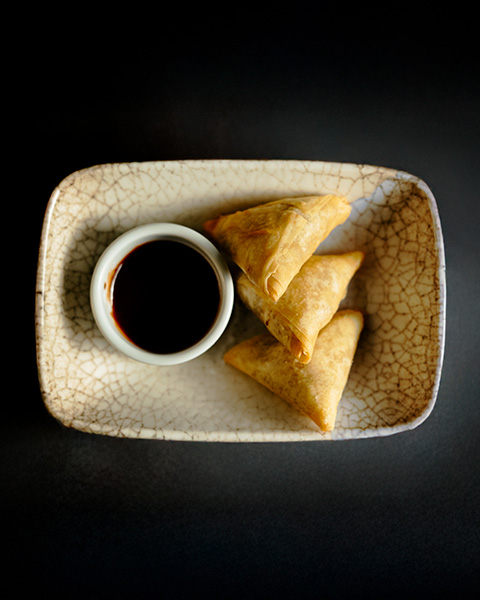 Crisp samosas served with dark tamarind chutney