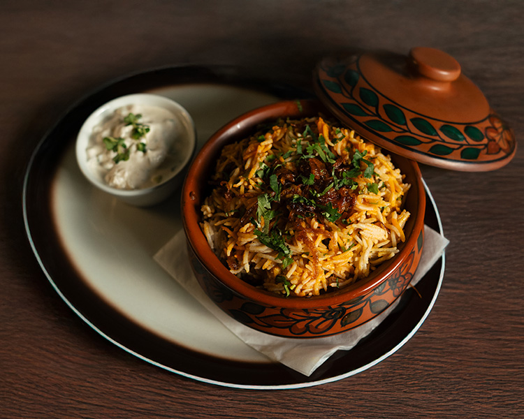 Chicken biryani served in a traditional handi with raita